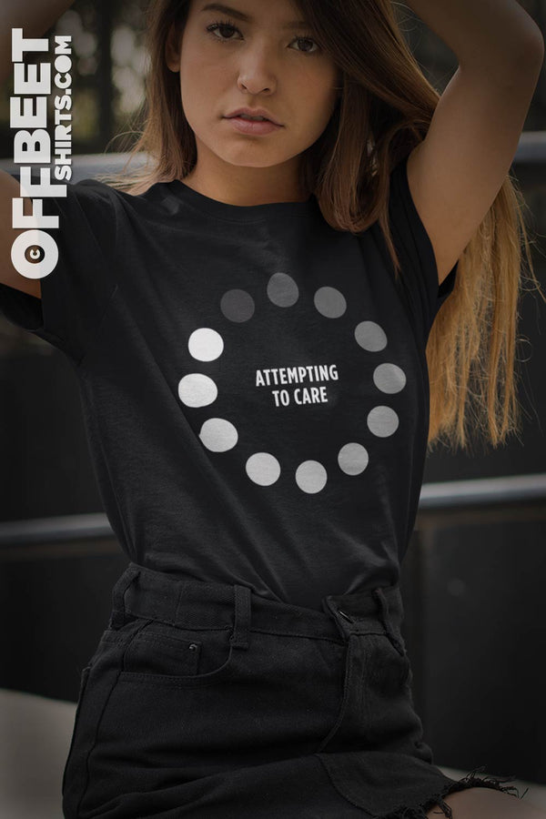 Attempting to Care Women’s Graphic T-shirt. A bit of satire for the impatient person in all of us. Circular internet video loading light to dark dots. Text: Attempting to Care Woman’s Black t-shirt  I  © 2019 Offbeet Shirts original design