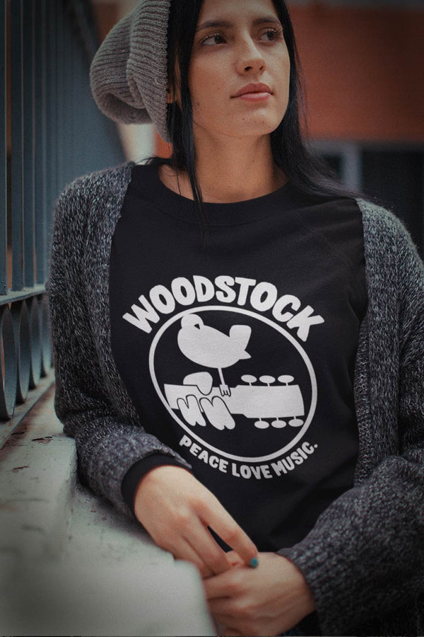 Woodstock graphic T-Shirt. Relive and celebrate the most iconic music festival in history. Woodstock surely was 3 days of peach and music.white graphic on black shirt dove settling on guitar neck with fingers over neck  I  Offbeet Shirts