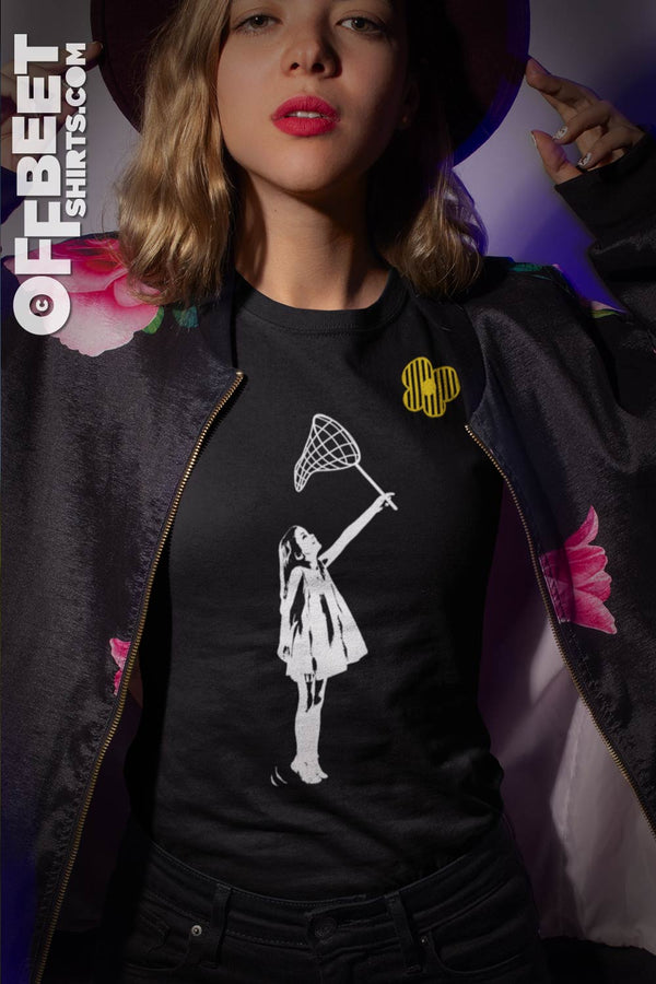 Sweet Little Predator Women’s Graphic T-shirt. Graphic of child with butterfly net reaching to catch a stylised butterfly White and yellow graphic on black women’s relaxed fit t-shirt ©Offbeet Shirts. 